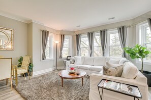 A spacious living room with a large window, a sofa, a coffee table, and a chair.