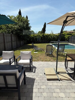 An outdoor patio with a pool, lounge chairs, and a wooden table. - New Listing (Sainte-Hélène)
