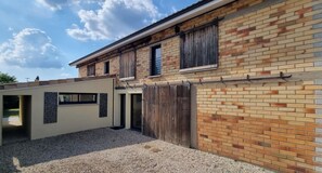 A two-story building with a brick facade, a wooden fence, and a gravel driveway. - New Listing (Sainte-Hélène)