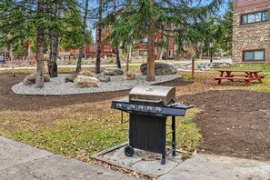 An outdoor barbecue grill with a stone building in the background. - Ski-In Breck Getaway | Community Hot Tub; Downtown Access (Breckenridge)