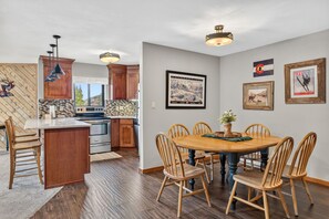 A modern kitchen with wooden cabinets, a central island, and pendant lighting. - Ski-In Breck Getaway | Community Hot Tub; Downtown Access (Breckenridge)