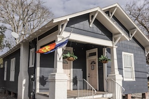 Una casa con porche, una bandera y dos macetas.