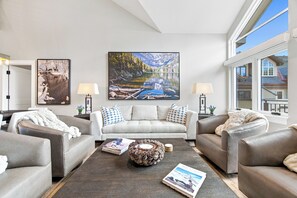 Ein modernes Wohnzimmer mit einem großen Gemälde von einem Bergsee, zwei Sofas, einem Couchtisch und zwei Lampen.