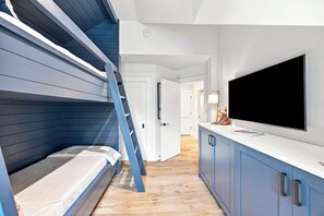 Ein Zimmer mit Stockbetten, einem Flachbildfernseher und Holzboden.