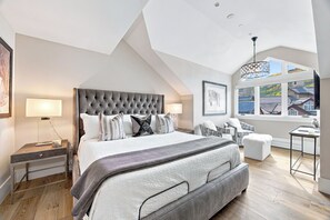 A bedroom with a large bed, a desk, a chair, and a window with a view of houses. - New Remodel Penthouse by InvitedHome | Walk to Ski/Town, Hot Tub, Pool, Gym (Beaver Creek)