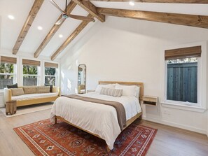 Une chambre avec un grand lit, un plafond en bois et une vue sur l’extérieur.