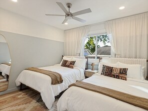 A hotel room with two beds, a ceiling fan, a window with curtains, and a view of the outside. - Newly Remodeled Western 3BR House With Cowboy Pool - Quiet and Great Location (Austin)