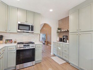 Une cuisine avec des meubles de couleur vert clair, une cuisinière en acier inoxydable et un four à micro-ondes.