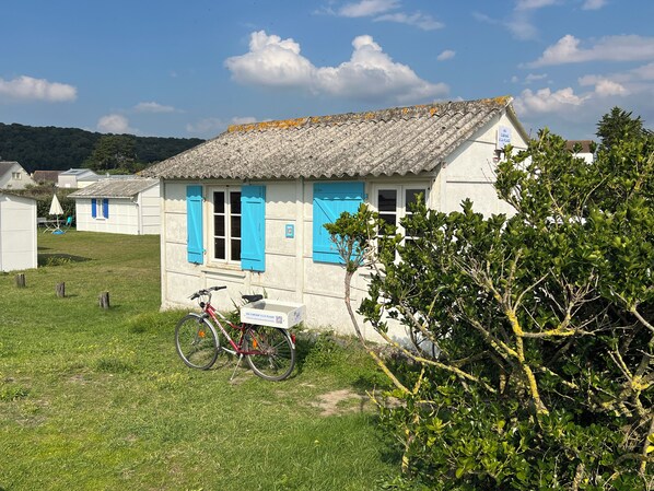A white building with blue shutters, a bicycle parked in front, and a sign indicating a car rental service.