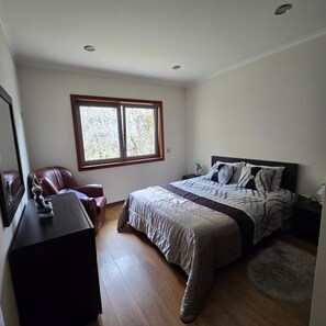 Une chambre à coucher comprenant un lit, un bureau, une chaise, une fenêtre et une table de chevet.