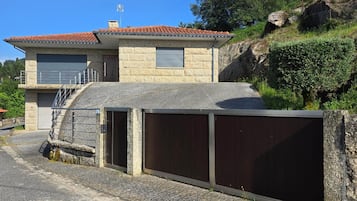 Un edificio de dos pisos con tejado de baldosas, garaje y fachada de piedra.