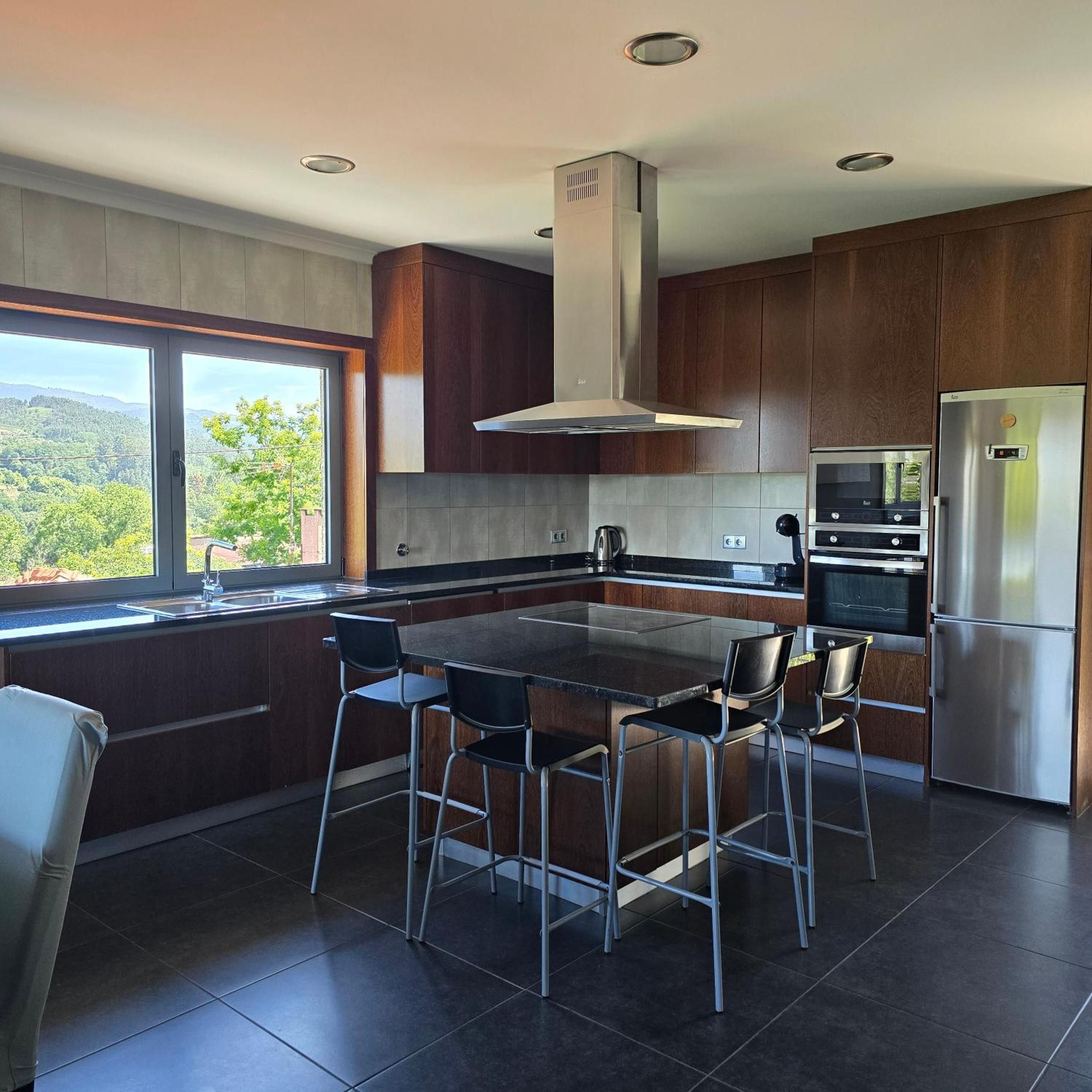 Cocina moderna con una isla grande, electrodomésticos de acero inoxidable y vistas al exterior.