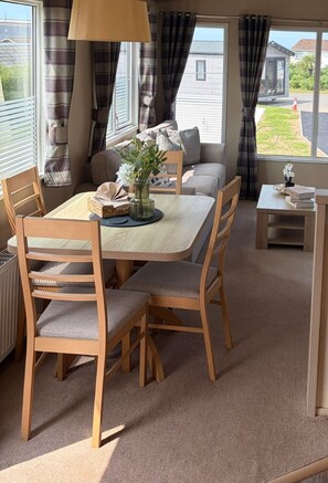 Un comedor con una mesa y sillas de madera, un sofá y vistas al exterior.