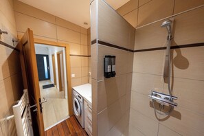 Ein kleines Badezimmer mit Waschmaschine, Dusche und Handtuchhalter.