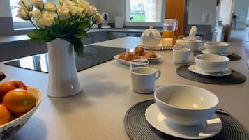 Una encimera de cocina con alimentos para el desayuno, un jarrón de flores y un frutero.