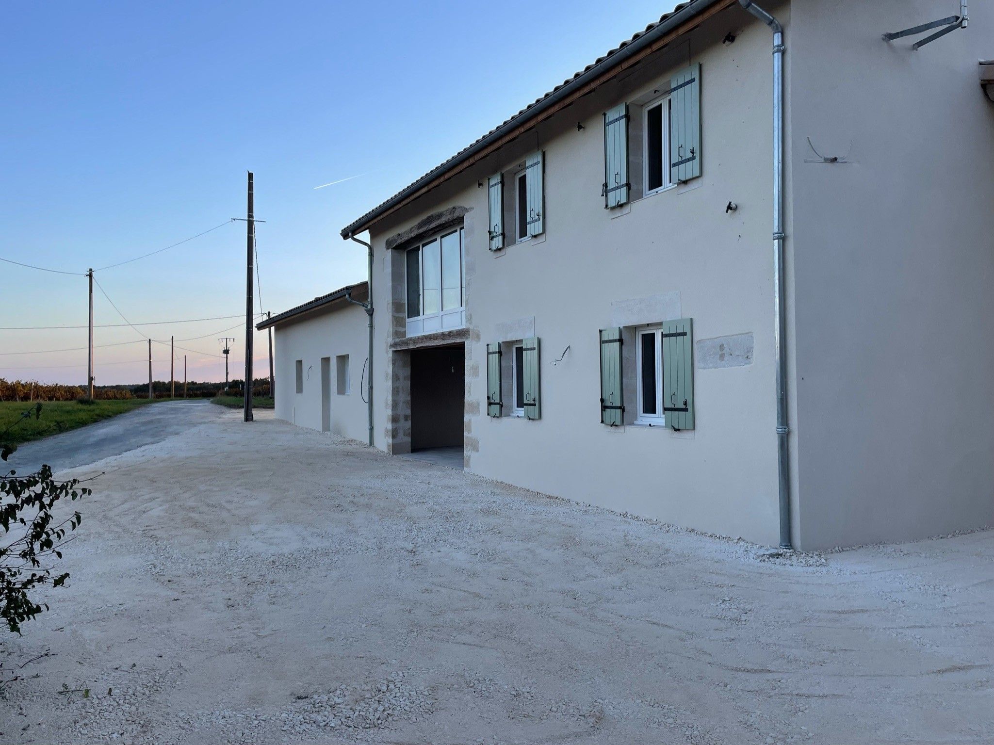 A two-story building with a gravel driveway and a clear sky.