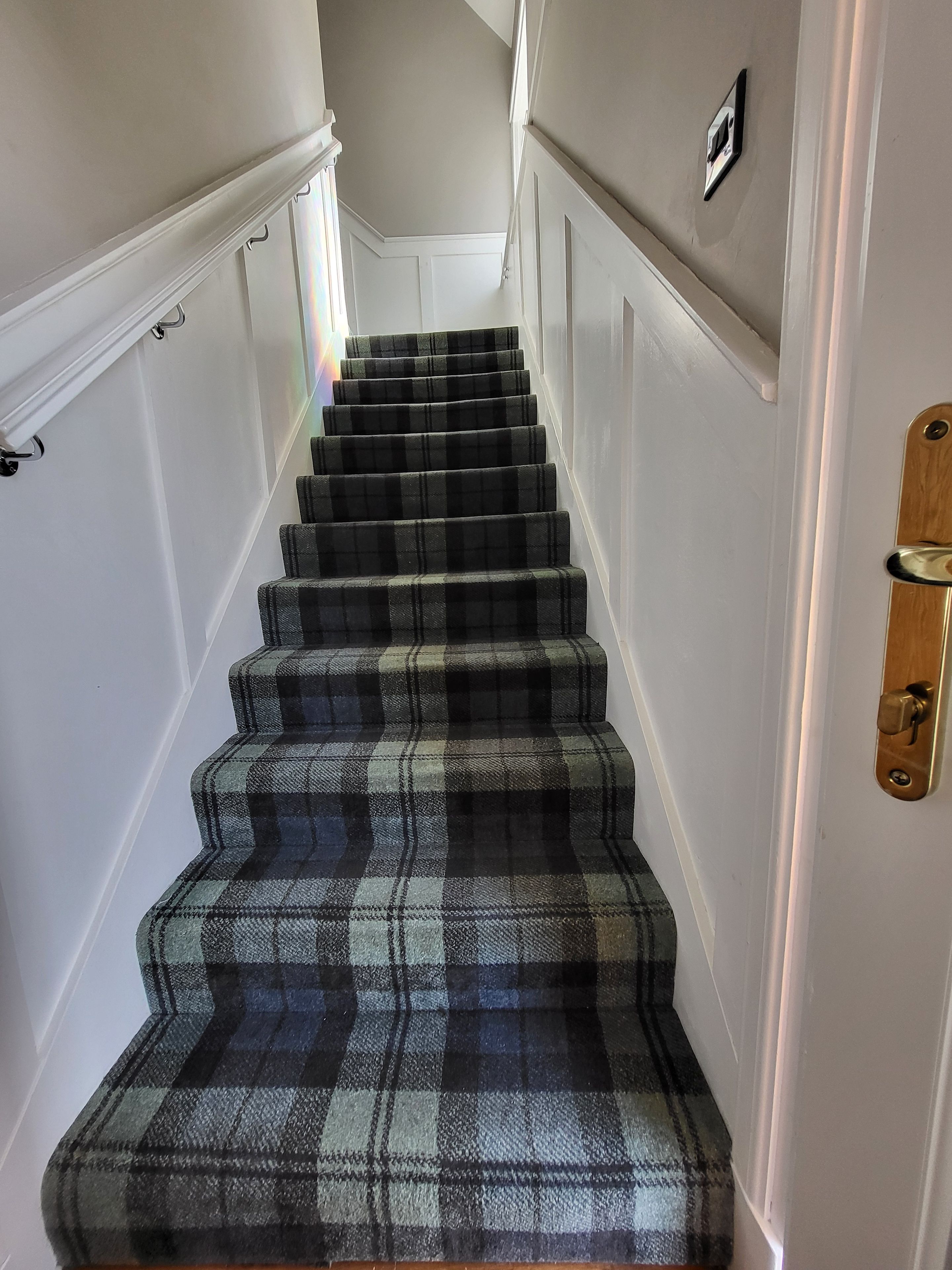 A staircase with a plaid carpet and white walls.