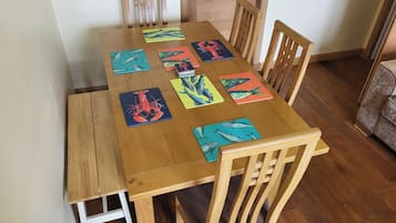 A wooden dining table with eight chairs, each with a colorful fish-themed placemat.