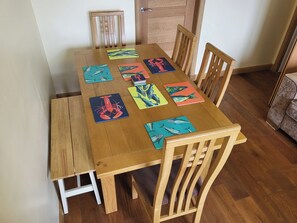 A wooden dining table with eight chairs, each with a colorful fish-themed placemat. - Bright upstairs flat with sea view, in Lossiemouth (Lossiemouth)