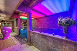 Un área de spa con pared de piedra, un gran arreglo floral y un banco de madera.