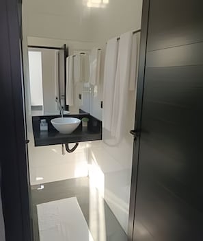 A modern bathroom with a large mirror, a white sink, and a towel rack. - Calaza Gestão Residencial (Porto Rico)