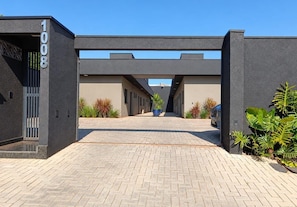 A modern building entrance with a paved driveway leading to a covered walkway. - Calaza Gestão Residencial (Porto Rico)