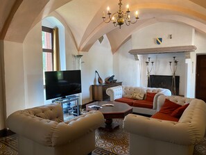 Un salon avec une télévision, une cheminée et un lustre.