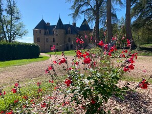 Ein Gebäude mit mehreren Türmen und einem gepflegten Garten mit roten Blumen.