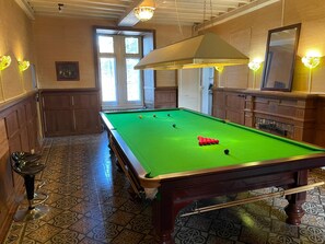 Une table de billard avec des billes, un miroir et un sol à motifs.