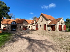Um edifício de pedra com várias portas vermelhas e uma entrada com calçada de cascalho.
