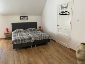 Quarto com cama, mesas de cabeceira, guarda-roupa e cabideiro.