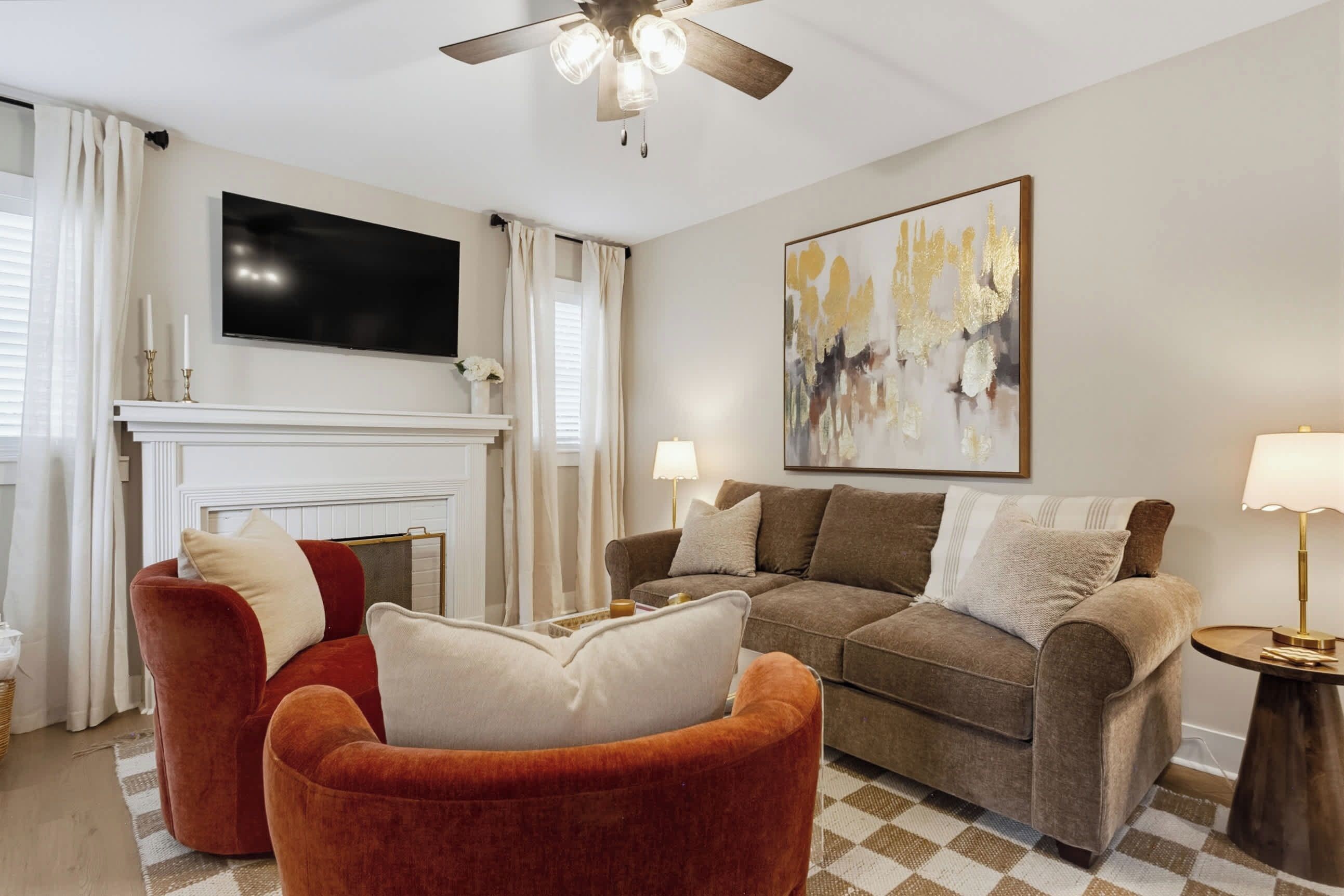 Un salon avec une cheminée, deux canapés, un téléviseur et un tableau accroché au mur.