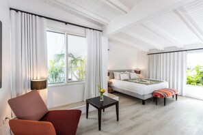 Ein Hotelzimmer mit einem Bett, einem Sessel, einem kleinen Tisch und Blick auf Grünflächen.