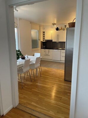 A modern kitchen with white cabinets, a stainless steel refrigerator, and a dining area with a white table and chairs. - New Listing (Handen)
