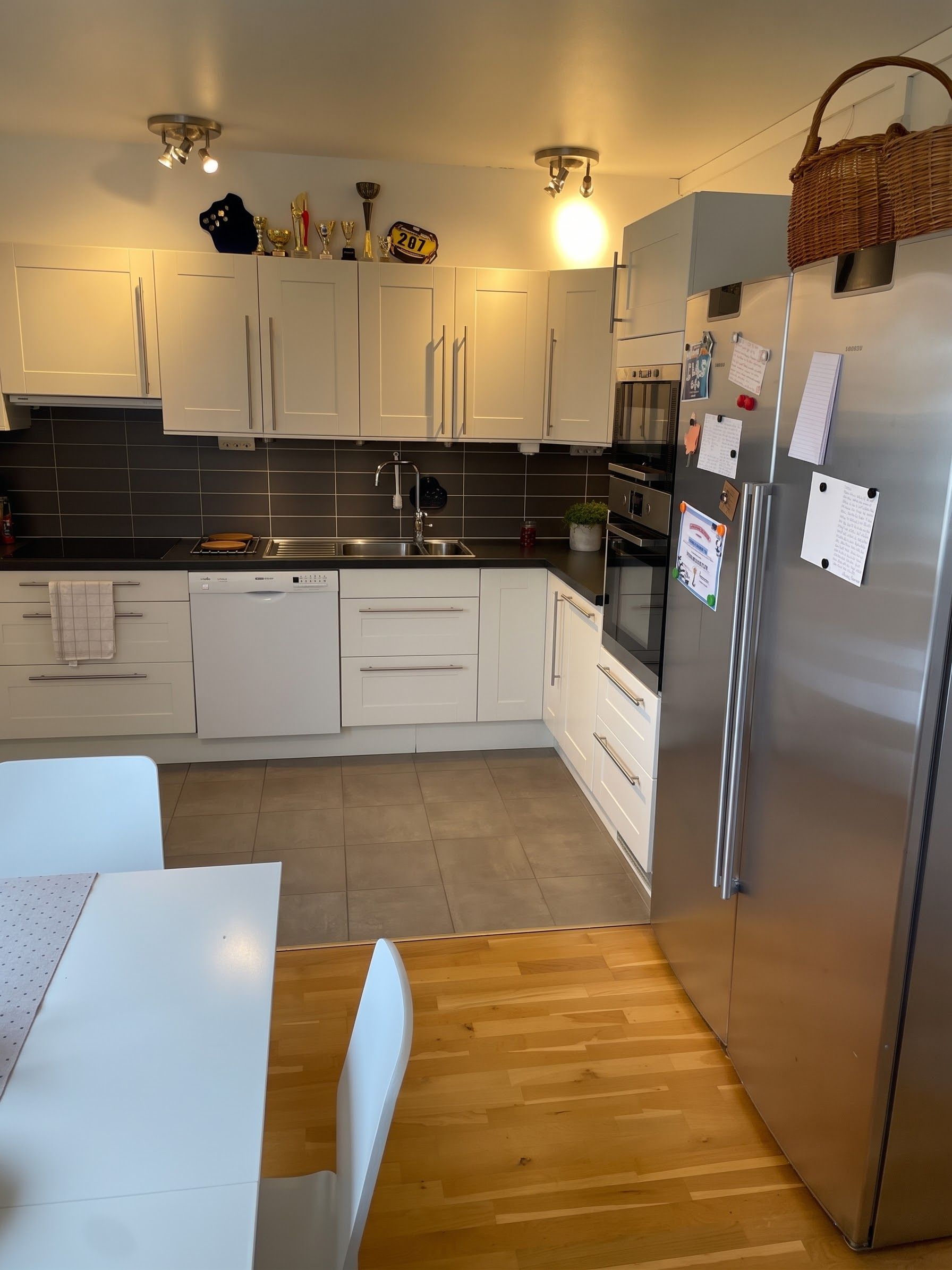 Una cocina moderna con armarios blancos, un refrigerador de acero inoxidable y un horno empotrado.