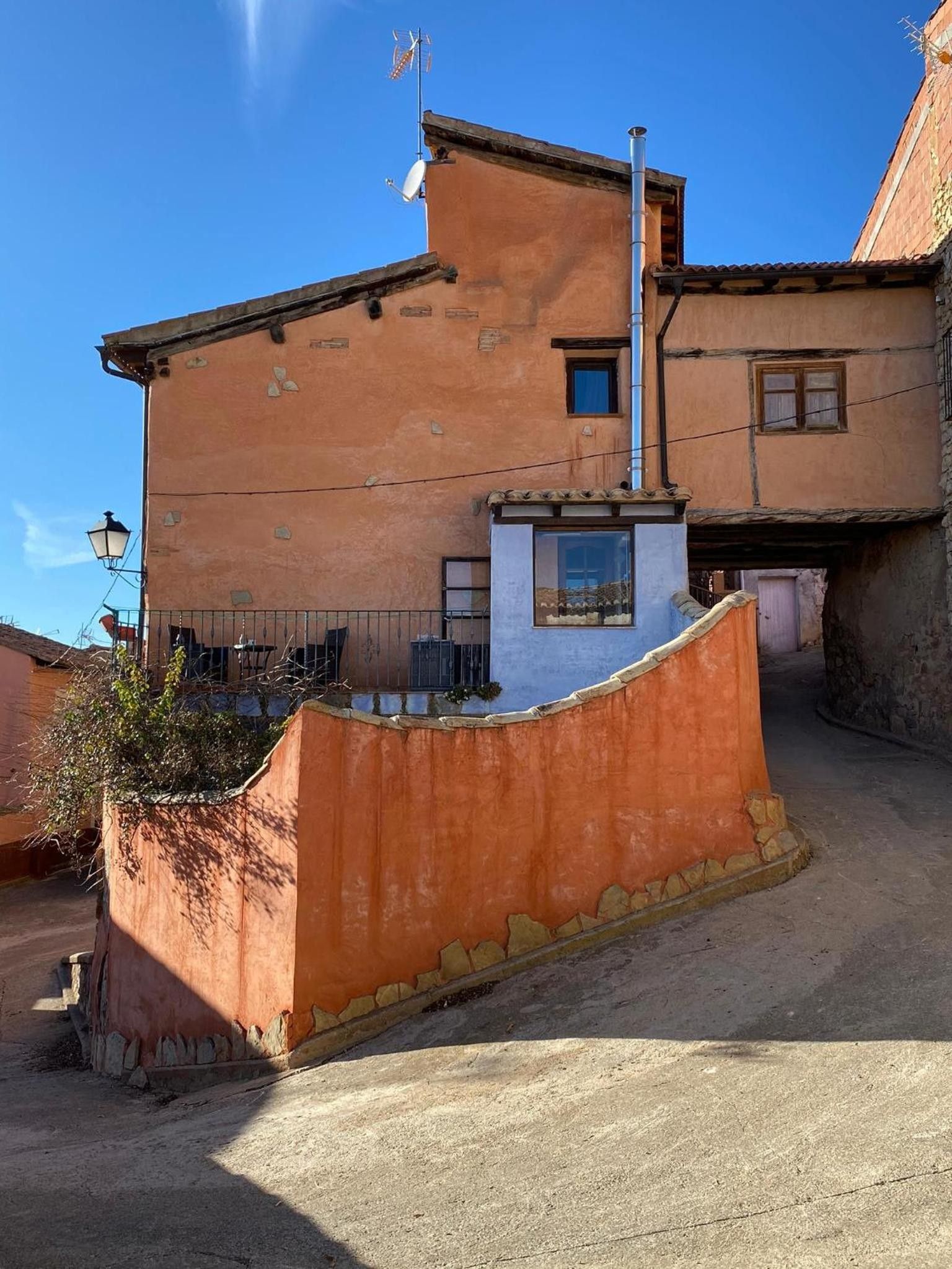 A two-story building with a sloped roof, a satellite dish, and a chimney.