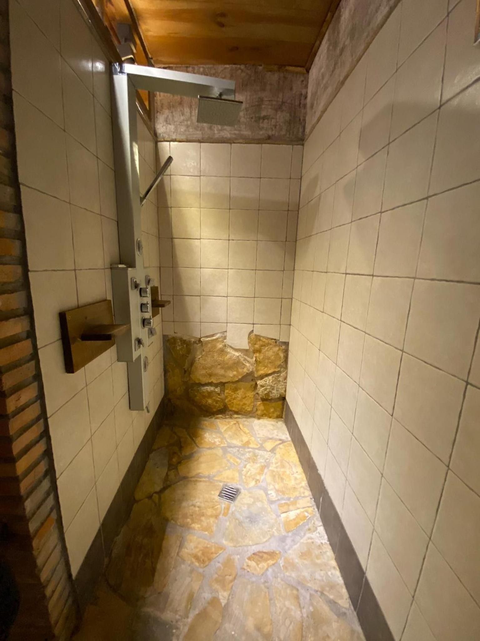 Un petit espace douche aux murs carrelés et au sol en pierre.