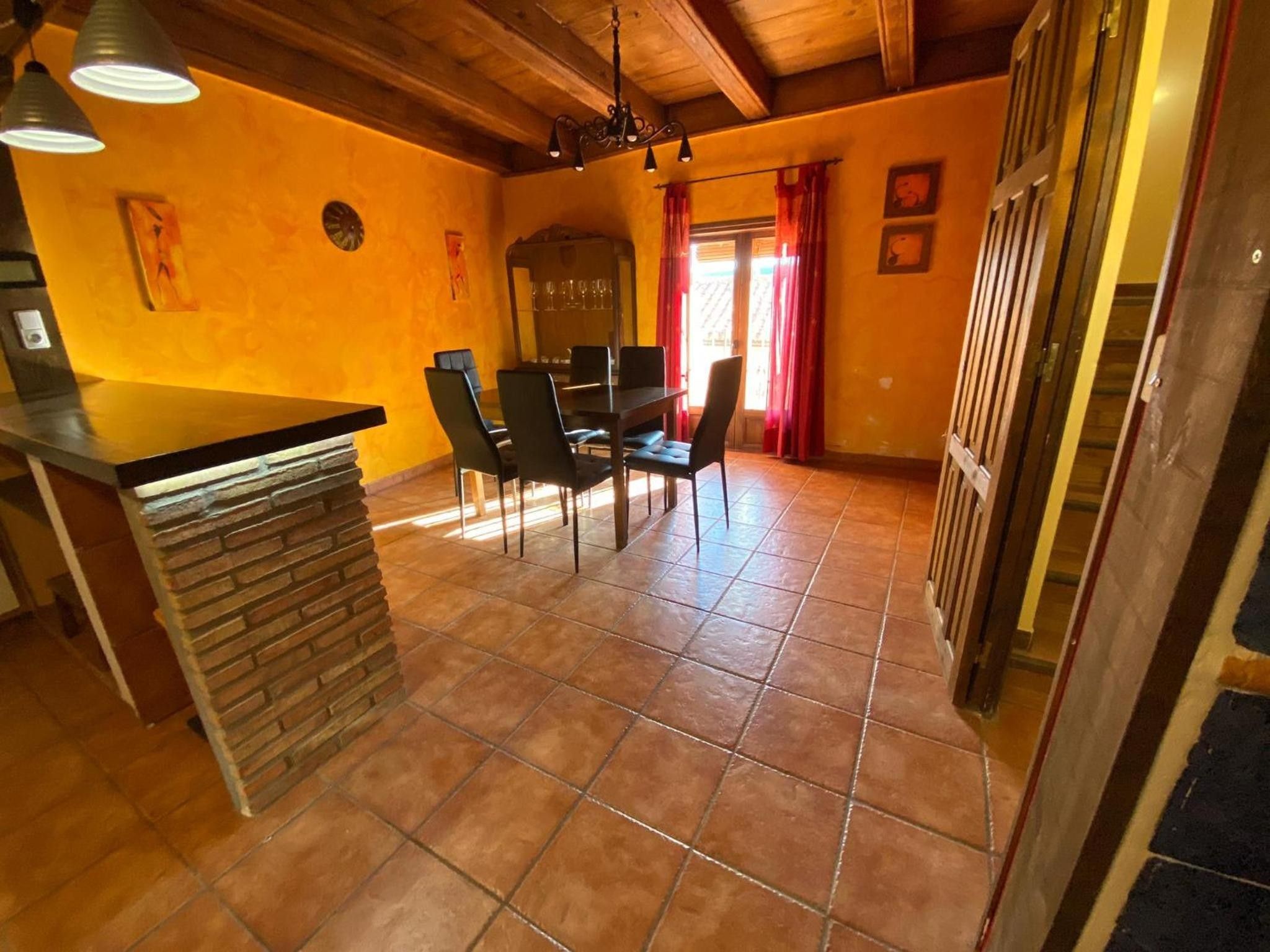 A dining area with a brick counter, wooden ceiling, and a dining table with chairs.
