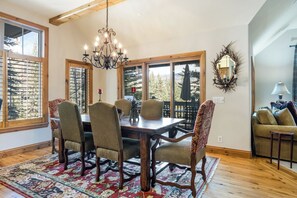 Uma sala de jantar com mesa de madeira, cadeiras e um candelabro.
