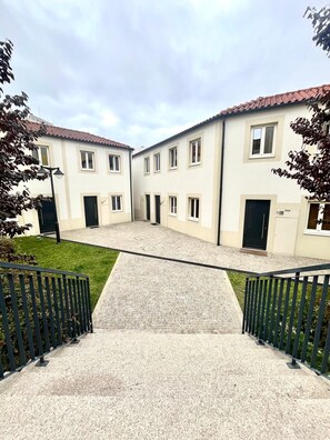 Une cour intérieure avec un chemin central menant à un bâtiment doté de nombreuses fenêtres et portes.