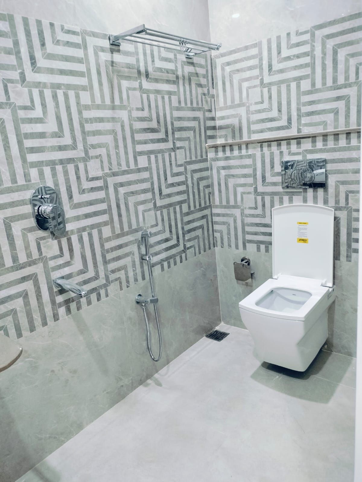 Un baño con ducha, inodoro y pared con diseño.