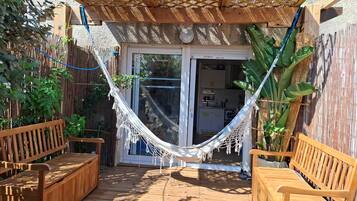 A wooden deck with a hammock, wooden benches, and a pergola structure.