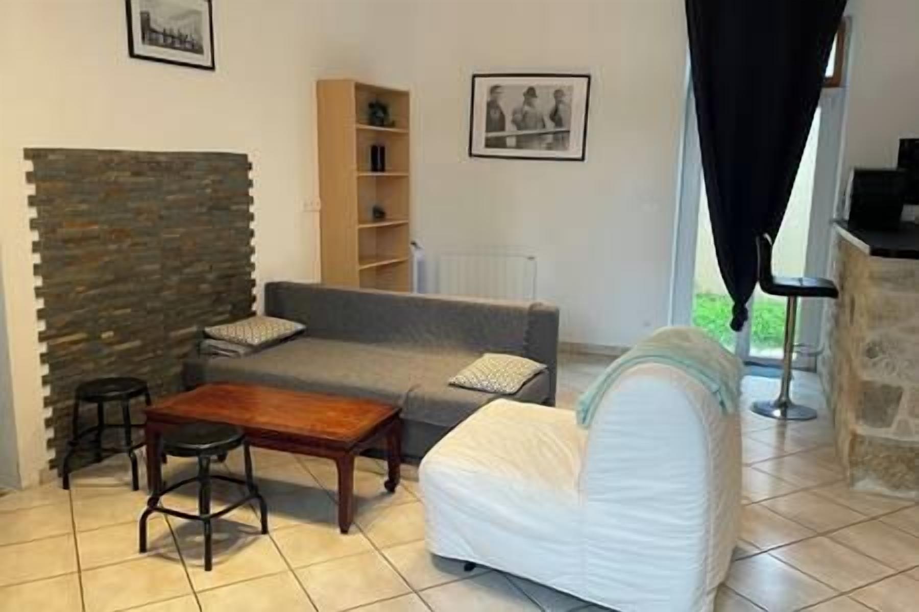 Uma sala de estar com parede de pedra, um sofá cinza, um sofá branco, uma mesa de centro de madeira e uma estante de livros.