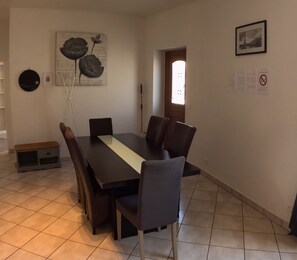 Ein Essbereich mit einem langen Tisch, Stühlen, einer Vase und Wandbildern.
