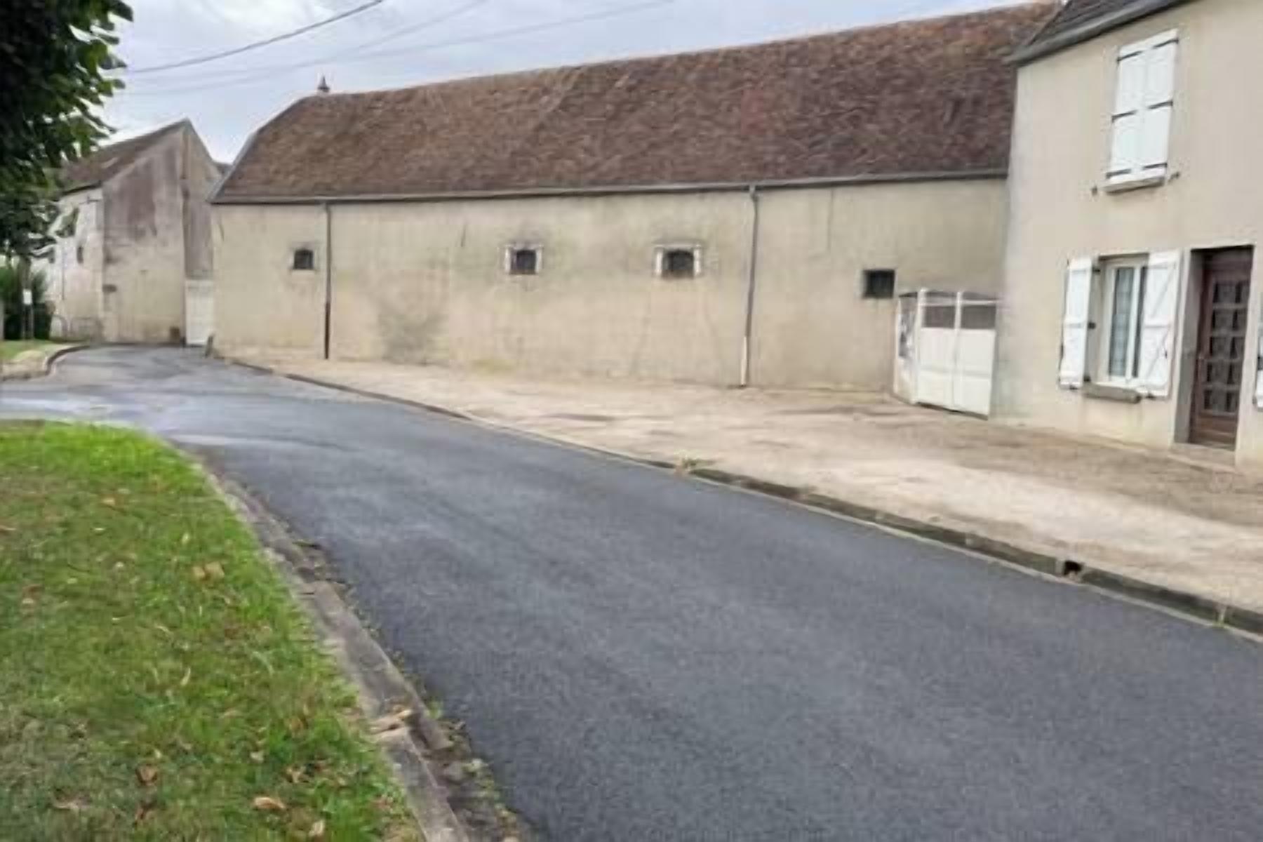 A quiet street with a building that has a flat roof and a garage door.