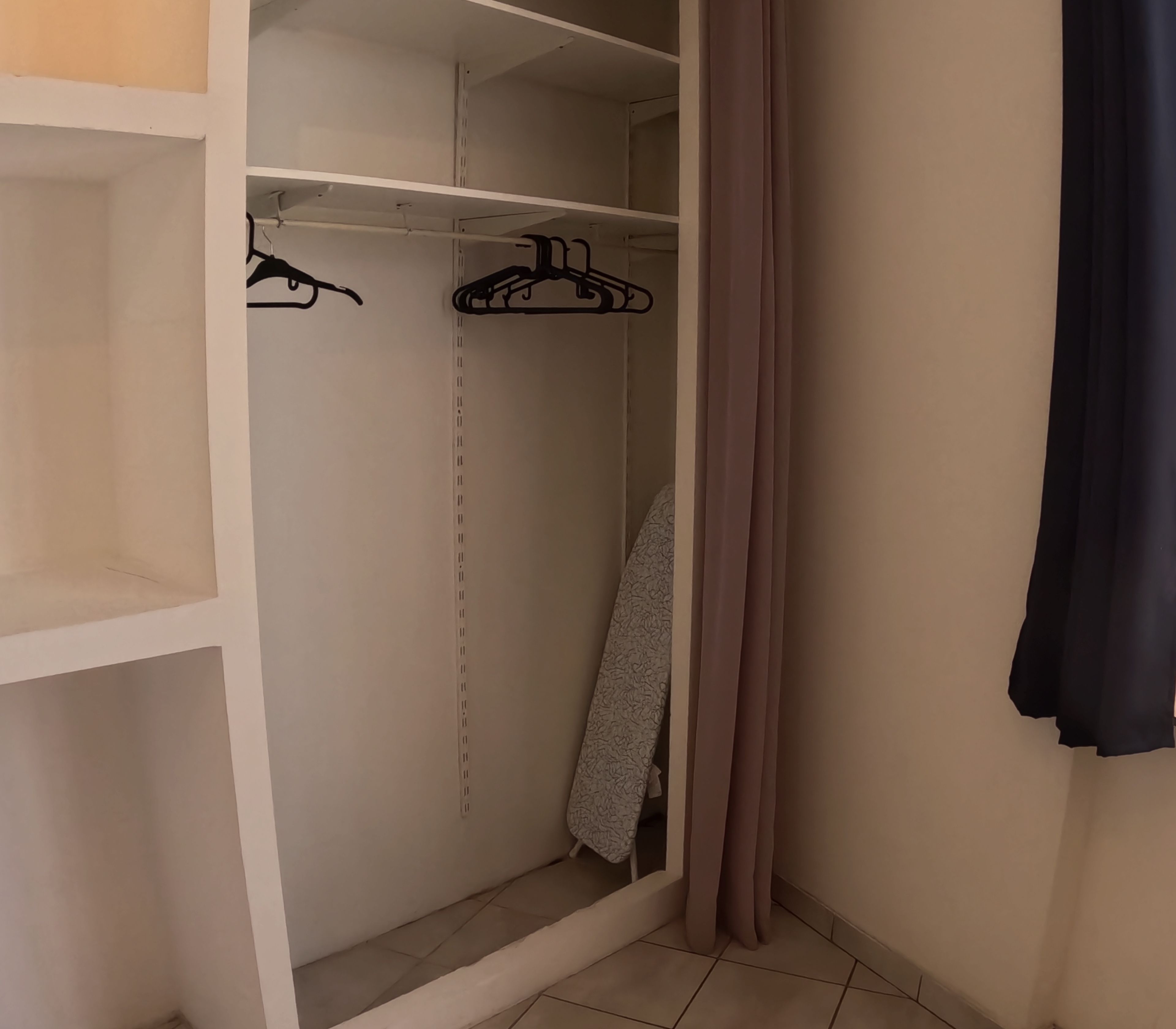 Un dressing avec espace pour suspendre les vêtements et des étagères.