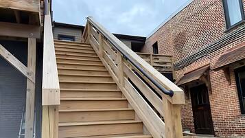 Una escalera de madera con barandilla metálica que conduce a un edificio de fachada de ladrillo.