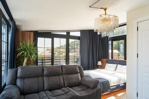 Een moderne slaapkamer met een groot raam, een bank, een bed en een kroonluchter.
