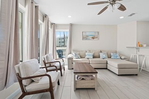 Un salon moderne avec un canapé d’angle, une table basse en bois et un ventilateur de plafond.