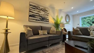 A modern living room with a grey sofa, a coffee table, a lamp, and a painting on the wall.